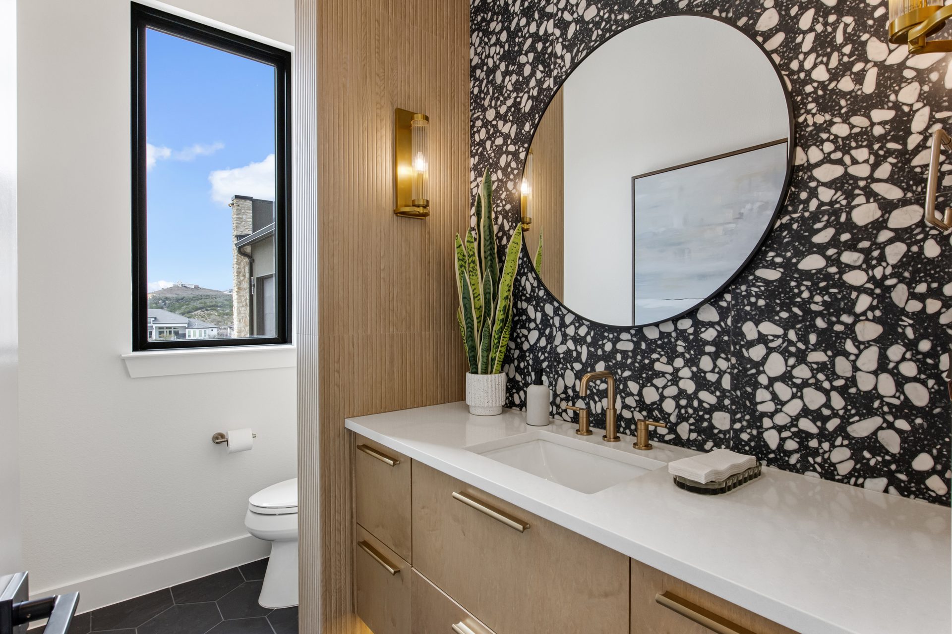 A custom powder bath with terrazzo tile, an oak vanity, and brass fixtures